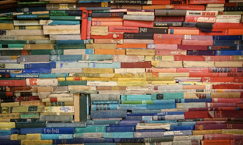 Unsortierter Stapel bunter Bücher, Symbol für das Chaos, das eine gute Content-Strategie ordnen muss.