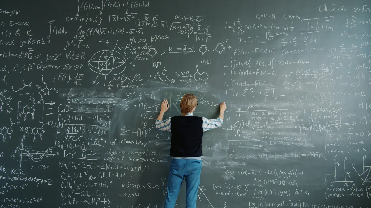 Eine Person schreibt an einer großen Tafel voller mathematischer Formeln und chemischer Strukturzeichnungen.
