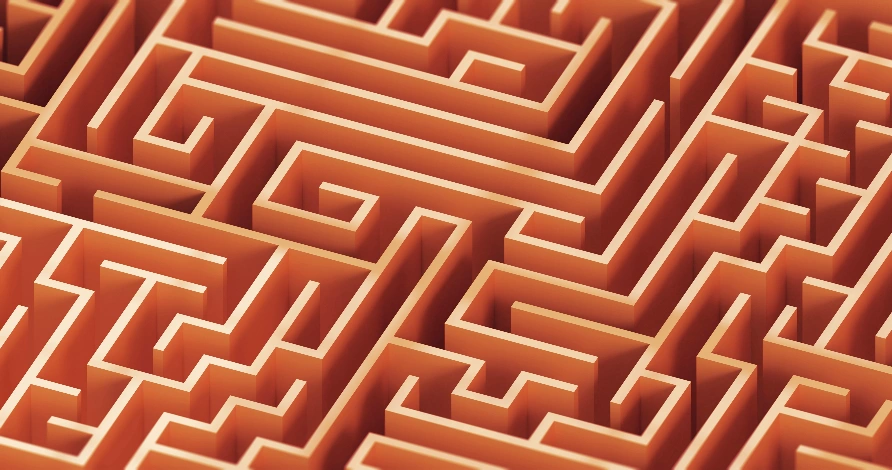 Komplexes, orangefarbenes Labyrinth aus der Vogelperspektive, symbolisiert die Herausforderungen im SEO und die Wichtigkeit klarer Webstrukturen.