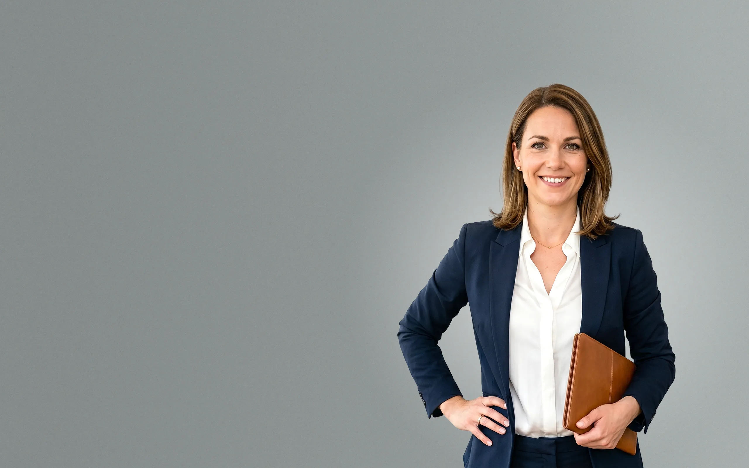 Professionelle Immobilienmaklerin im Business-Anzug mit Ledermappe lächelt freundlich – Symbolbild für SEO, SEA und Lead-generierendes Webdesign für die Immobilienbranche.