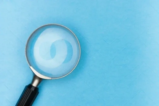 Lupe auf einem blauen, strukturierten Hintergrund, die eine genaue Untersuchung symbolisiert.
