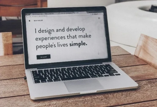 Offener MacBook Pro Laptop auf einem Holztisch zeigt eine minimalistische Design-Website.