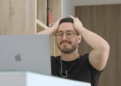 Ein frustrierter Mann hält sich den Kopf, nachdem ein fehlerhaftes WordPress-Update seine Website lahmgelegt hat.