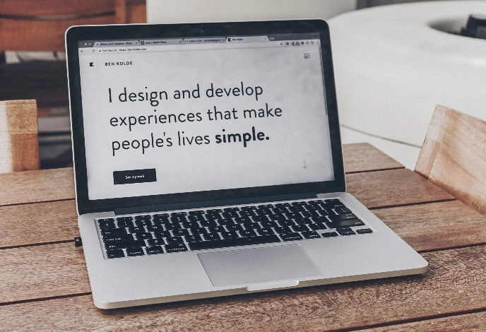 Offener MacBook Pro Laptop auf einem Holztisch zeigt eine minimalistische Design-Website.