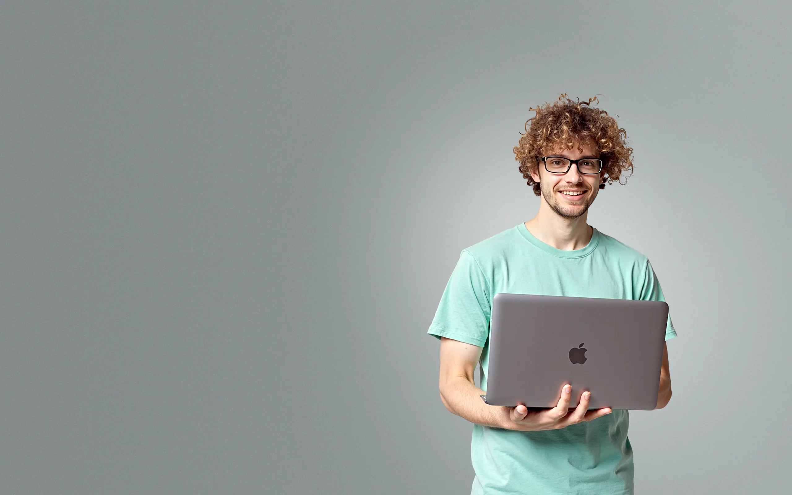 Junger Mann mit Laptop lächelt in die Kamera – steht für zuverlässige Website-Wartung und technische Pflege Ihrer Website
