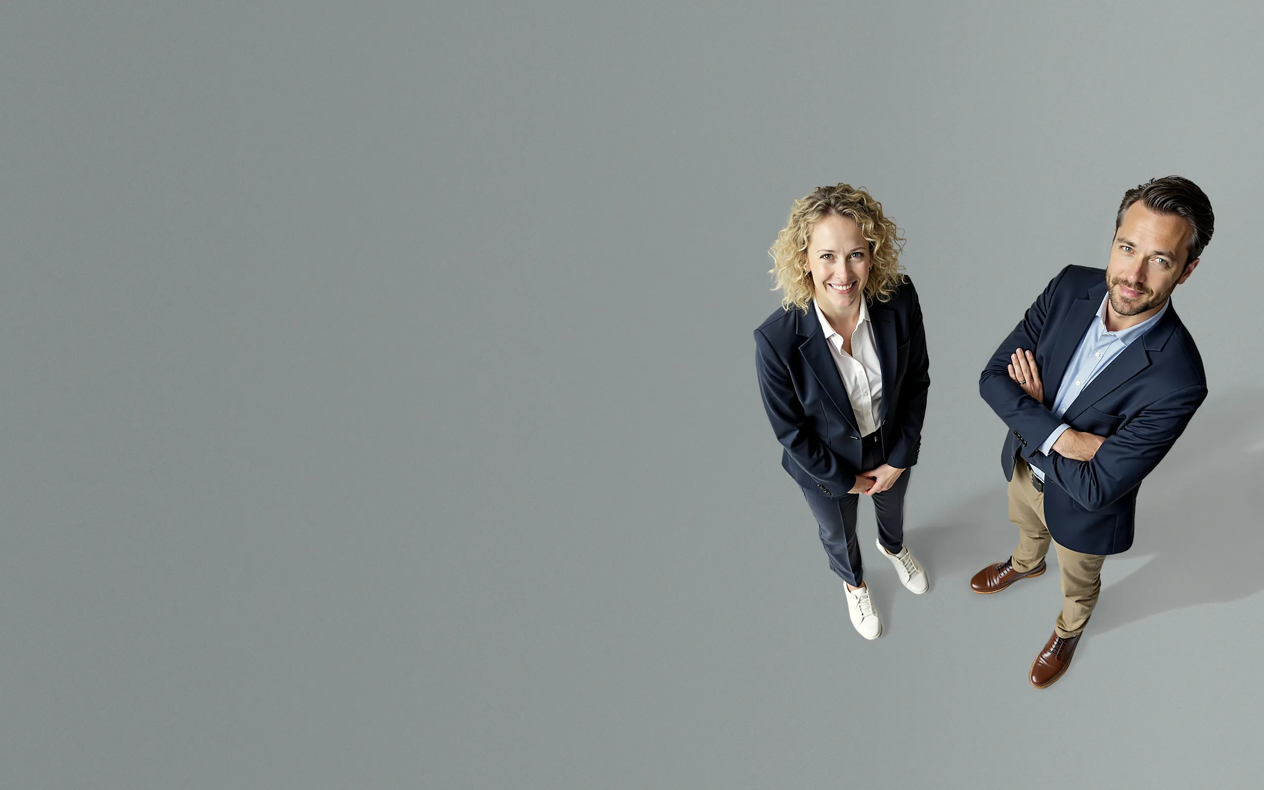 Zwei erfolgreiche Unternehmer stehen selbstbewusst vor grauem Hintergrund – symbolisch für professionelles Webdesign, das verkauft und nicht nur gefällt